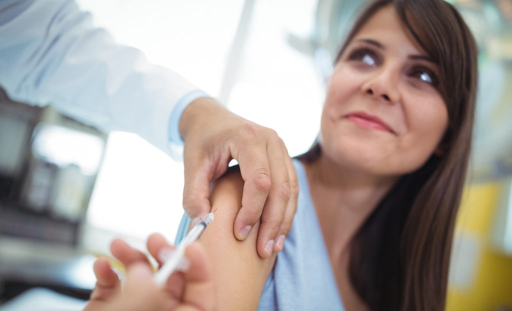 Medico inietta il vaccino contro l'influenza a una paziente