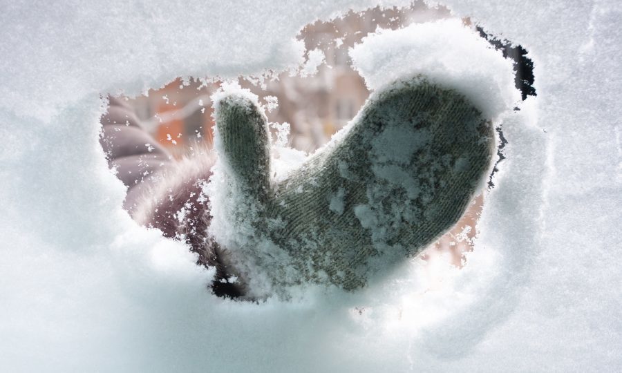 Una mano pulisce la neve dal parabrezza