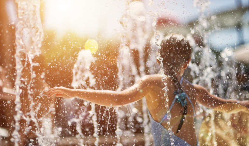 Una bambina si rinfresca in una fontana pubblica