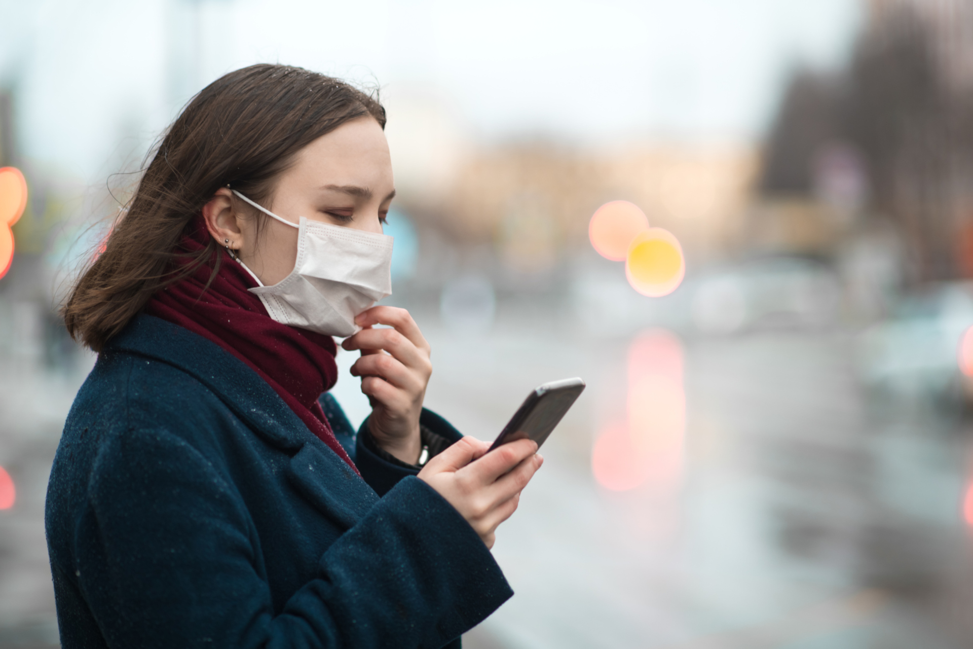 Ragazza con la mascherina e lo smartphone