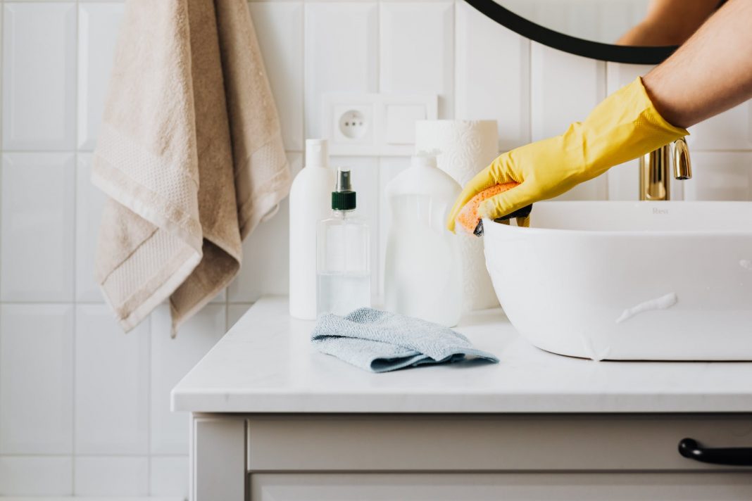 pexels-photo-4239113 person in glove wiping surface of sink in modern bathroom