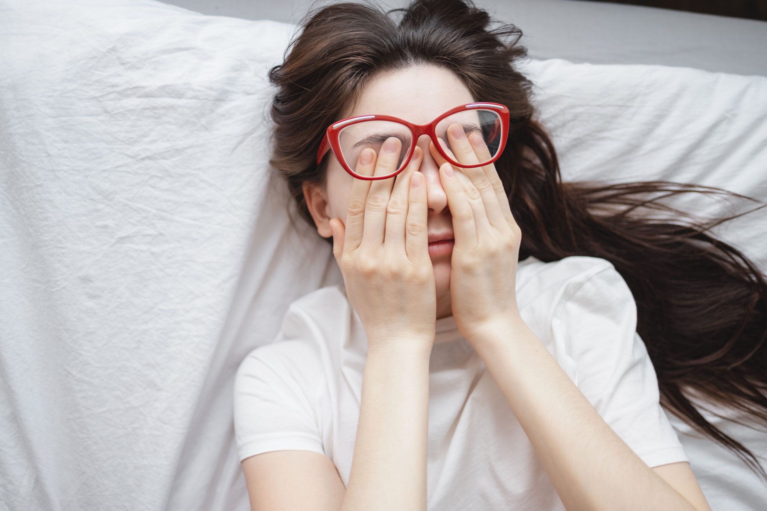 young woman rubs her eyes after using glasses. eye pain or fatig